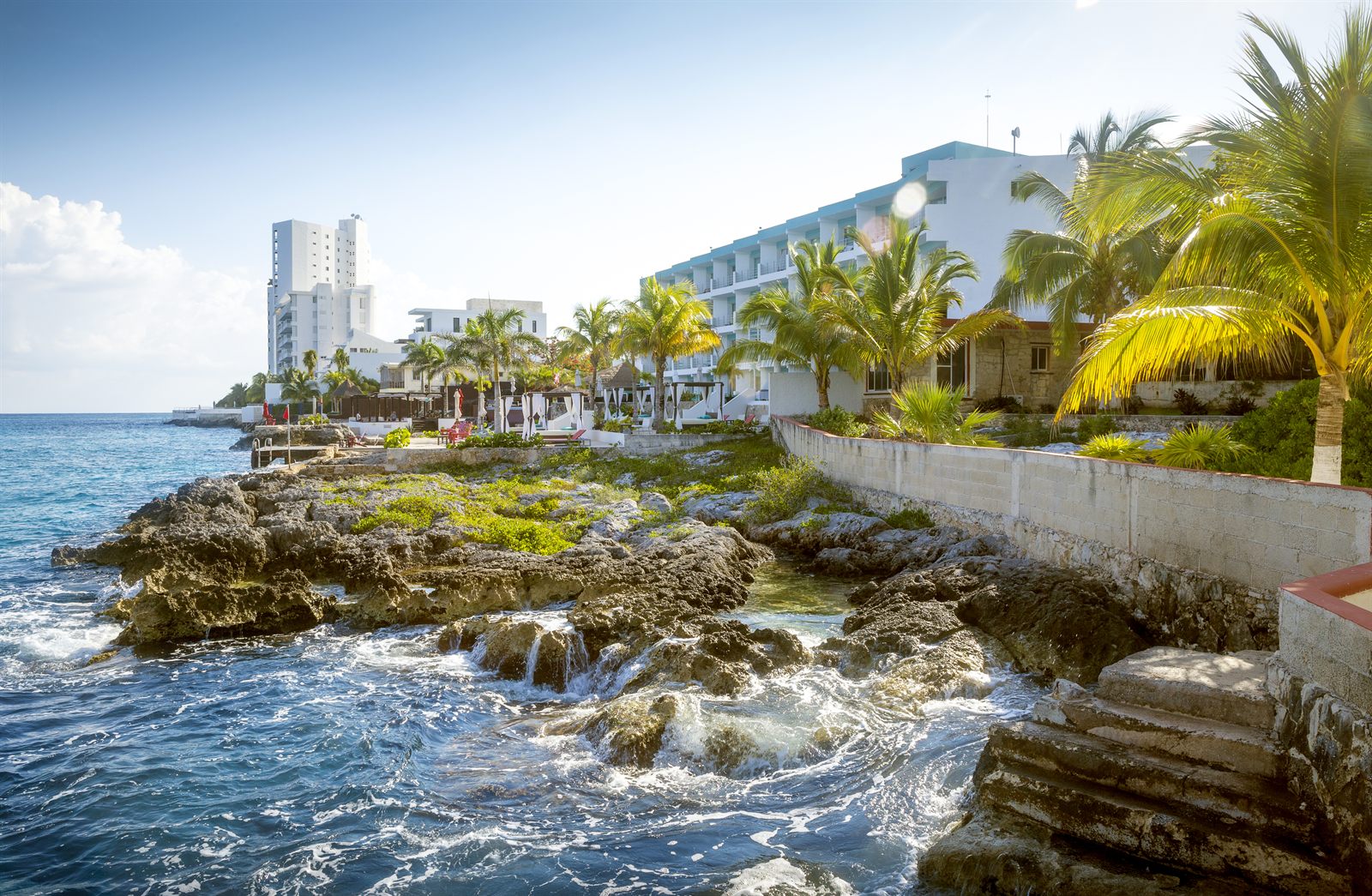 Rocky limestone shoreline and seafront hotels on the island of Cozumel